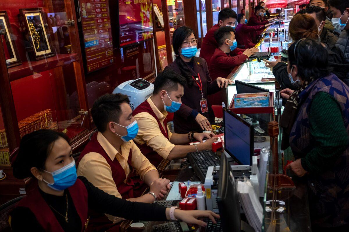 Gold shop employees wear face masks while serving customers in Hanoi, Vietnam, on Feb. 3, 2020. (Linh Pham via Getty Images)