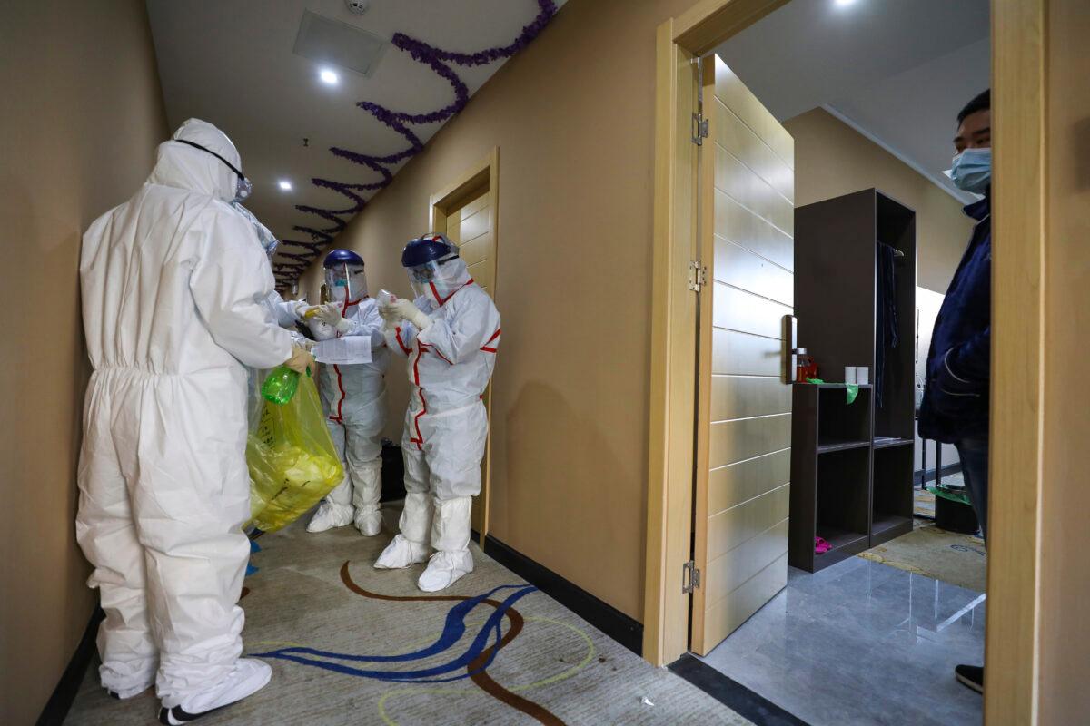 A patient waits as medical workers in protective suits prepare to collect a sample for nucleic acid tests at a hotel being used to place suspected virus patients in medical isolation in Wuhan in central China's Hubei Province on Feb. 4, 2020. (Chinatopix via AP)