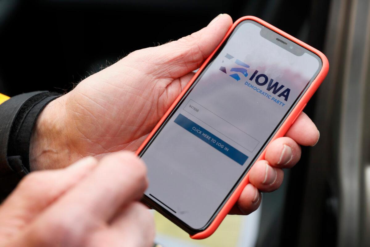 Precinct captain Carl Voss, of Des Moines, Iowa, holds his iPhone that shows the Iowa Democratic Party's caucus reporting app in Des Moines, Iowa, on Feb. 4, 2020. (Charlie Neibergall/AP Photo)