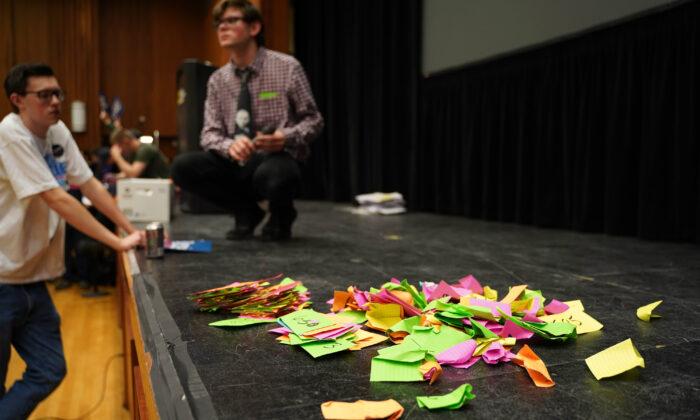 Bits of paper are distributed to each voter upon entry at an Iowa Democratic caucus in Iowa City on Feb. 3, 2020. (Cara Ding/The Epoch Times)
