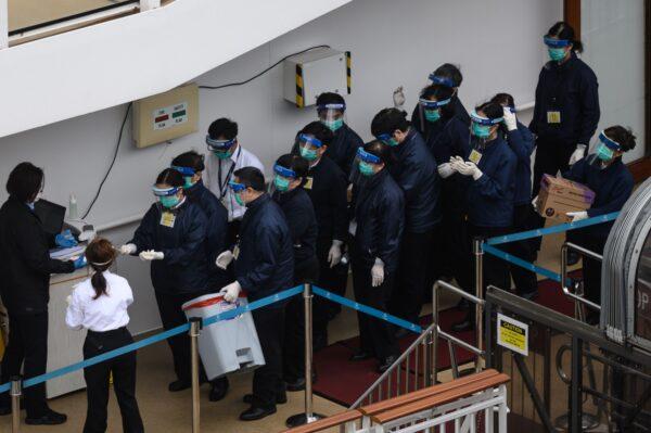 Members of the Hong Kong Department of Health wearing protective gear queue up to clean their hands on the deck of the World Dream cruise ship, docked at the Kai Tak cruise terminal in Hong Kong on Feb. 5, 2020 (Philip Fong/AFP via Getty Images)