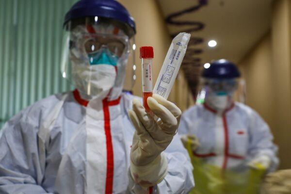 A medical staff member showing a test tube after taking samples taken from a person to be tested for the new coronavirus at a quarantine zone in Wuhan, China on Feb. 4, 2020. (STR/AFP via Getty Images)