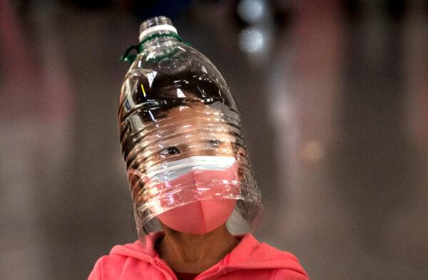 A Chinese girl wears a plastic bottle as makeshift homemade protection and a protective mask while waiting to check in on a flight at Beijing Capital Airport in Beijing, China, on Jan. 30, 2020. (Kevin Frayer/Getty Images)