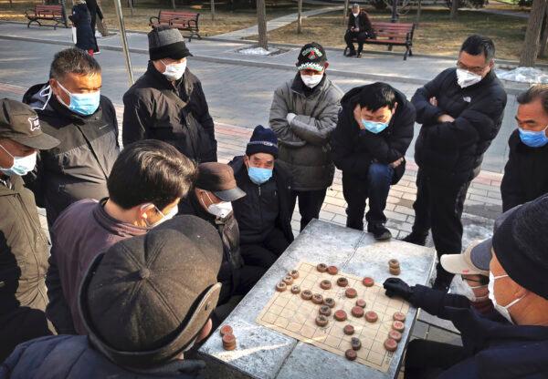 Chinese men all wear protective masks as they play mahjong at a park in Beijing, China on Jan. 31, 2020. (Kevin Frayer/Getty Images)