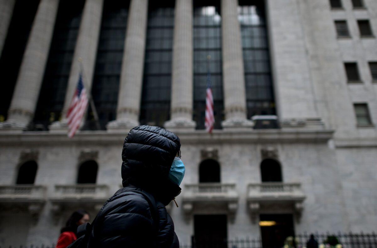 A woman with a facial mask passes the New York Stock Exchange (NYSE) on Wall Street in New York City on Feb. 3, 2020. (Johannes Eisele/AFP via Getty Images)