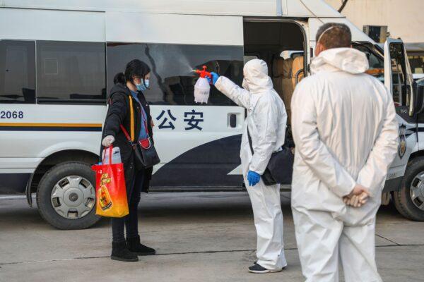 A medical staff member (C) spraying disinfectant on a patient after returning from a hospital and reentering a quarantine zone in Wuhan, in China's central Hubei province, on Feb. 3, 2020. (STR/AFP via Getty Images)
