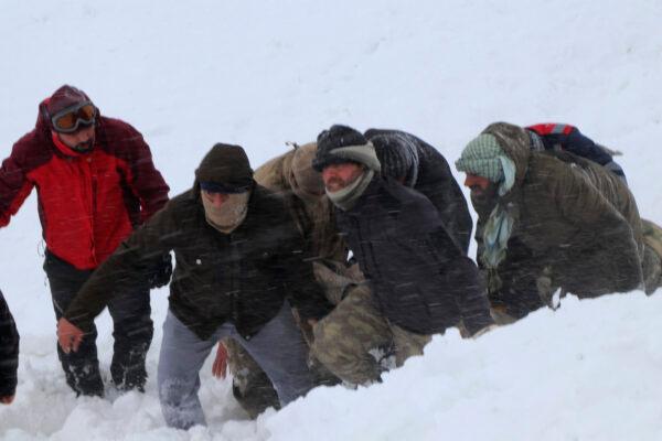 Emergency service members work in the snow around overturned vehicles, near the town of Bahcesaray, Van province, eastern Turkey, on Feb. 5, 2020. (Yilmaz Sonmez/IHA via AP)