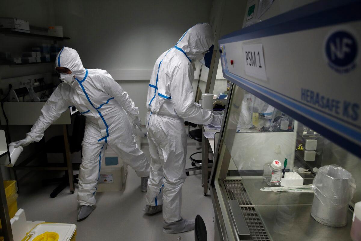 French lab scientists in hazmat gear inserting liquid in test tube manipulate potentially infected patient samples at Pasteur Institute in Paris on Feb. 6, 2020. (Francois Mori/AP Photo)