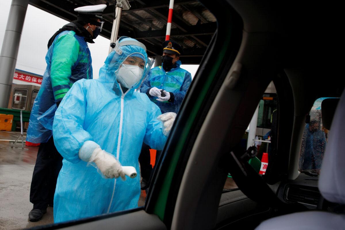 A medical worker checks a driver's temperature at a checkpoint as the country is hit by an outbreak of the novel coronavirus in Anqing, Anhui province, China, on Feb. 6, 2020. (Thomas Peter/Reuters)