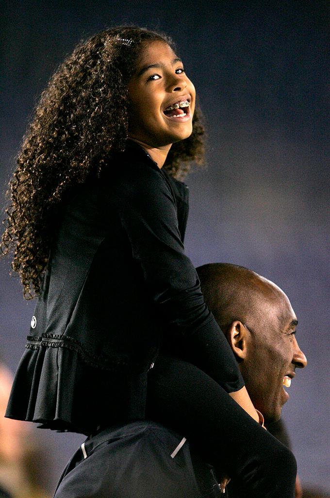 Bryant on the sideline with daughter Gianna on his shoulders at Qualcomm Stadium in San Diego, California, on April 10, 2014 (©Getty Images | <a href="https://www.gettyimages.com/detail/news-photo/los-angeles-laker-kobe-bryant-stands-on-the-sideline-with-news-photo/484010293?adppopup=true">Kent C. Horner</a>)