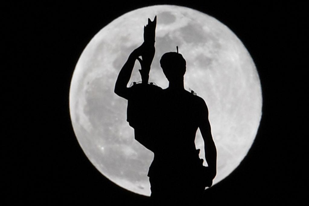 A statue atop Milan's Duomo Cathedral is pictured as the Super Snow Moon rises on Feb. 19, 2019. (©Getty Images | <a href="https://www.gettyimages.com/detail/news-photo/statue-atop-milans-duomo-cathedral-is-pictured-as-the-super-news-photo/1125887379?adppopup=true">ANDREAS SOLARO</a>)
