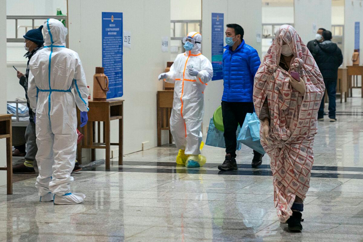 Medical workers in protective suits help patients diagnosed with the coronavirus as they arrive at a temporary hospital which was repurposed from an exhibition center in Wuhan in central China's Hubei Province on Feb. 5, 2020. (Chinatopix via AP)