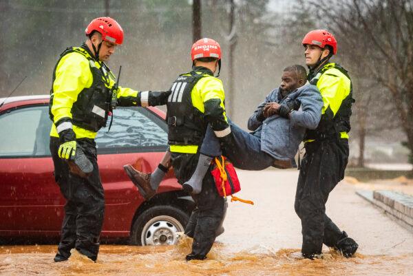 Winston-Salem Fire Department firefighters with the Rescue Task Force rescue Donald Harold from his home at Liberty Landing Apartments as flood waters rise around the building in Winston-Salem, N.C., on Feb. 6, 2020. (Andrew Dye/The Winston-Salem Journal via AP)