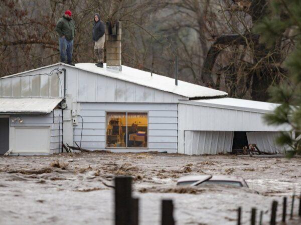 Nate Fuller and Archie Morrow await rescue on the roof of a home in Thorn Hollow outside of Adams, Ore., on Feb. 6, 2020. (Ben Lonergan/East Oregonian via AP)