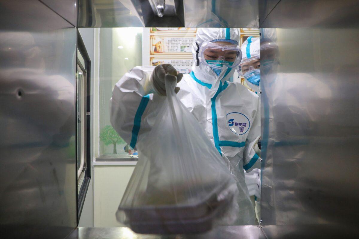 A medical staff member getting lunch boxes for patients through a window in an isolation ward at a hospital in Wuhan in China's central Hubei province, during the virus outbreak in the city, on Jan. 30, 2020. (STR/AFP via Getty Images)