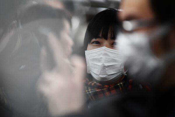 Commuters wearing face masks ride a metro train in Tokyo on Feb. 8, 2020. (Charly Triballeau/AFP via Getty Images)