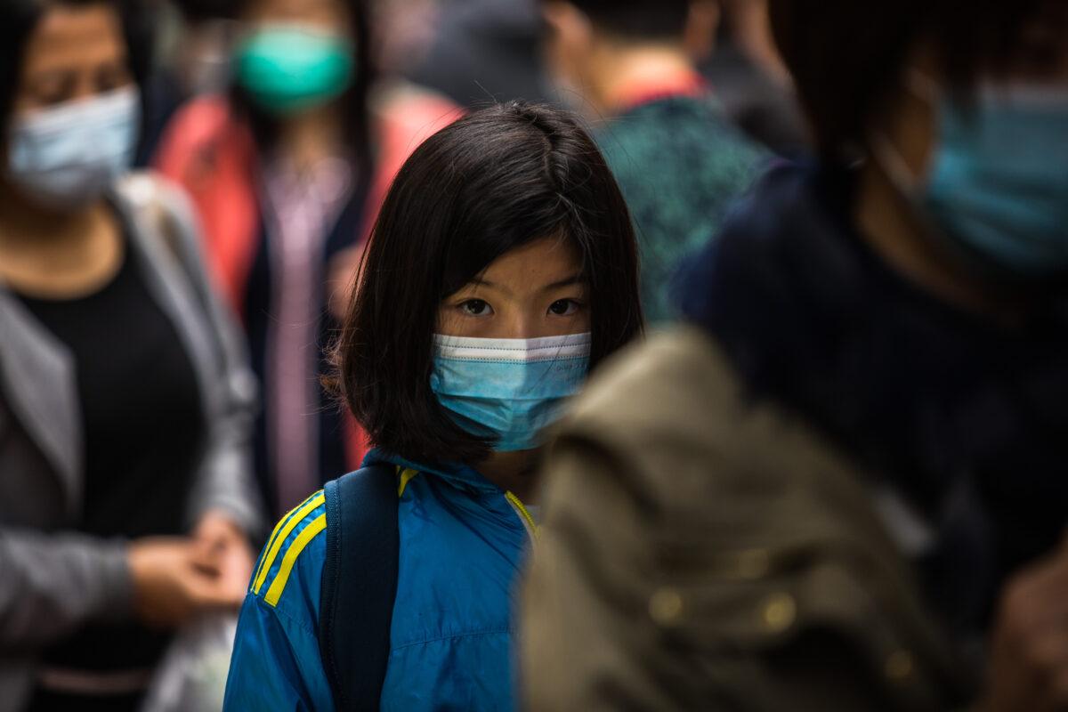 People wearing protective face masks walk along a street in Hong Kong on Feb. 9, 2020. (Dale De La Rey/AFP via Getty Images)