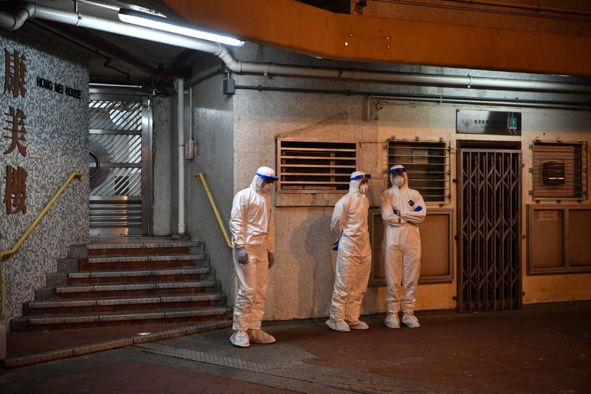 Medical personnel stand outside a block in the ground of a residential estate, in Hong Kong, early on Feb. 11, 2020, after two people in the block were confirmed to have contracted the coronavirus according to local newspaper reports. (Anthony Wallace/AFP via Getty Images)
