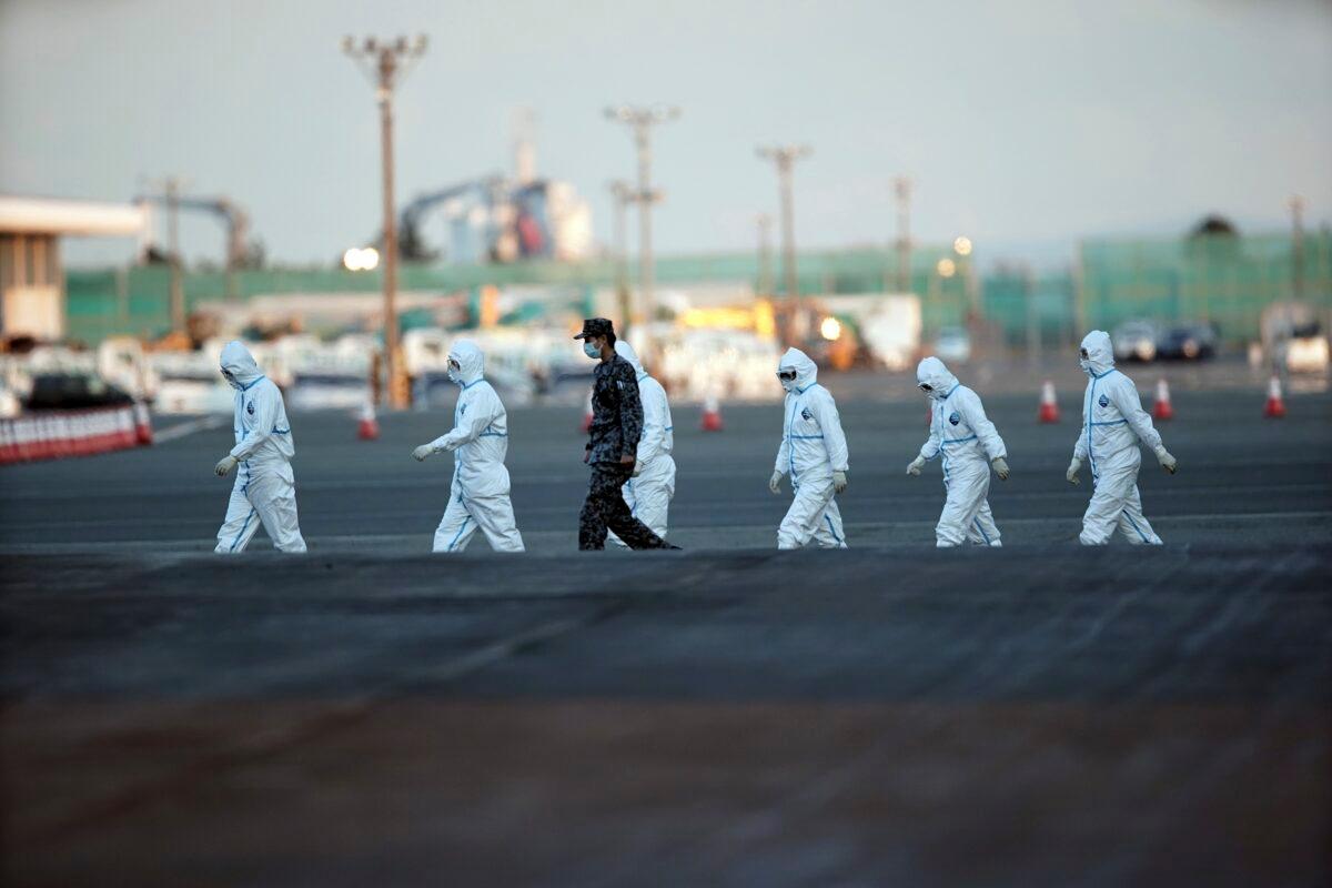 Officials with protective suits walk from the quarantined cruise ship Diamond Princess in the Yokohama Port in Japan on Feb. 10, 2020. (Eugene Hoshiko/AP Photo)