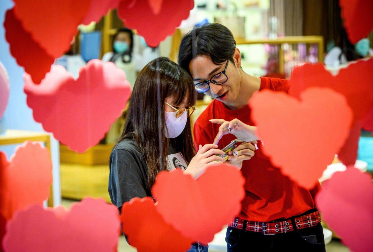 An employee talks to a woman wearing a protective facemask behind Saint Valentine's decorations in a shopping mall in Bangkok on Feb. 11, 2020. (Mladen Antonov/AFP via Getty Images)