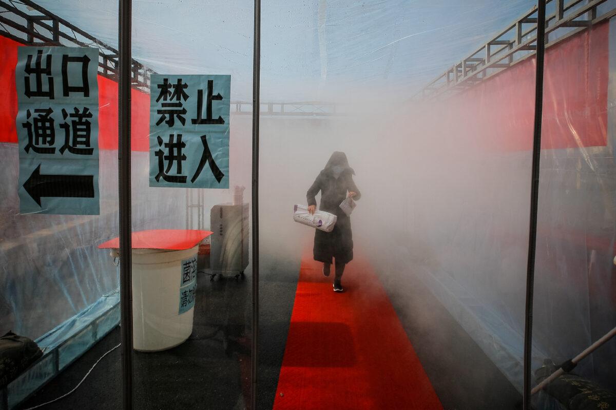 A woman wearing a face mask walks through a device that sprays disinfectant at an entrance to a residential compound, following an outbreak of the novel coronavirus in the country, in Tianjin, China on Feb. 11, 2020. (cnsphoto via Reuters)