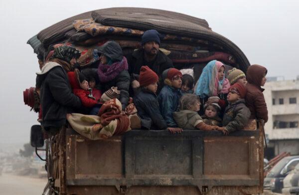 Internally displaced Syrians from western Aleppo countryside, ride on the back of a truck with belongings in Hazano near Idlib, Syria, on Feb. 11, 2020. (Khalil Ashawi/Reuters)