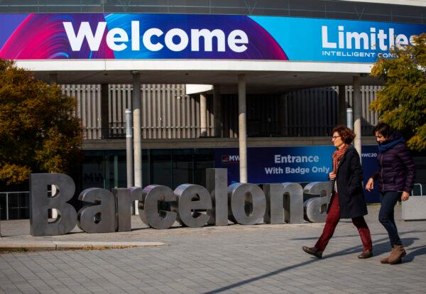 People walk past posters announcing the Mobile World Congress 2020 in a conference venue in Barcelona, Spain, on Feb. 11, 2020. (Emilio Morenatti/AP Photo)