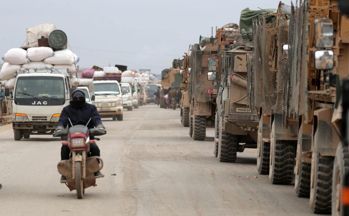 A man rides on a motorbike past Turkish military vehicles in Hazano near Idlib, Syria, on Feb. 11, 2020. (Khalil Ashawi/Reuters)