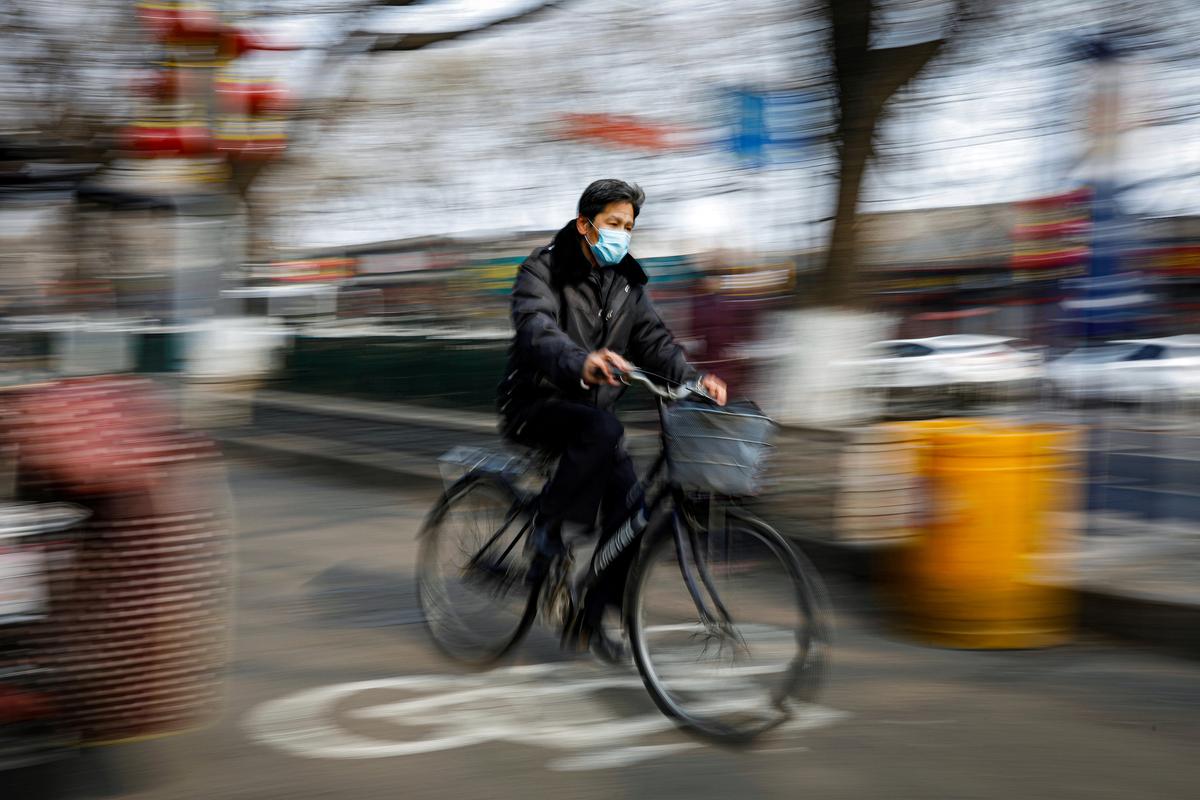 A man wearing a face mask rides a bicycle, as the country is hit by an outbreak of the Novel Coronavirus, in Beijing, China, on Feb. 12, 2020. (Carlos Garcia Rawlins/Reuters)