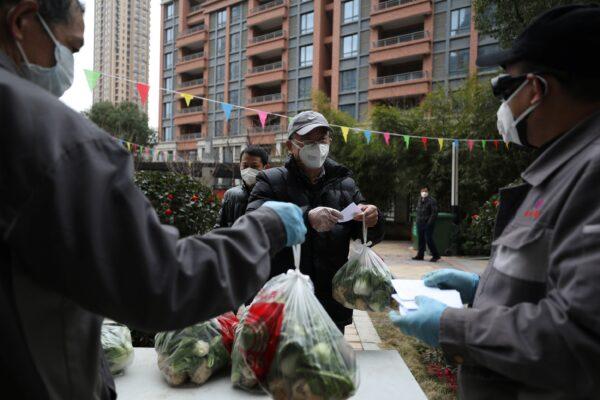 Community workers distribute free vegetables to members of households inside the residential compound, following the outbreak of the novel coronavirus in Wuhan, Hubei province, China on Feb. 11, 2020. (China Daily via Reuters)