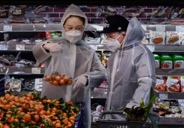 A Chinese couple wearing plastic coats and protective masks shop for groceries at a supermarket in Beijing, China, on Feb. 11, 2020. (Kevin Frayer/Getty Images)