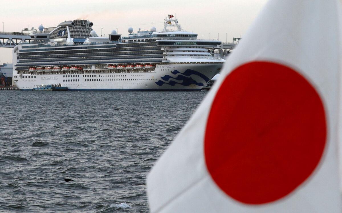 The cruise ship Diamond Princess is pictured beside a Japanese flag as it lies at anchor while workers and officers prepare to transfer passengers who tested positive for coronavirus, at Daikoku Pier Cruise Terminal in Yokohama, Japan, on Feb. 12, 2020. (Kim Kyung-Hoon/ Reuters)
