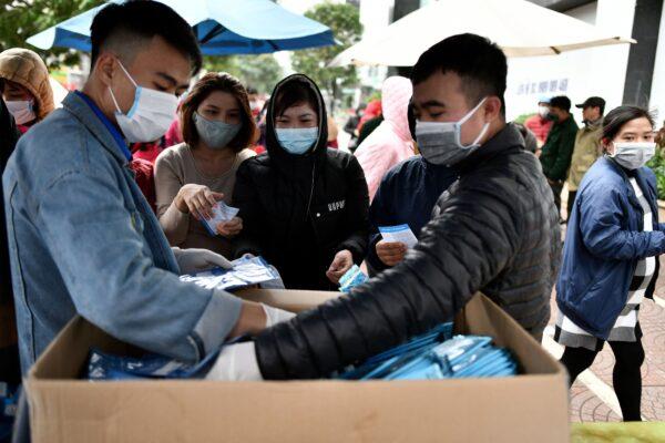 Vietnamese residents (C) receive free protective face masks at a makeshift distribution center amid concerns of the Novel Coronavirus outbreak, in Hanoi on Feb. 8, 2020. (Manan Vatsyayana/AFP/Getty Images)