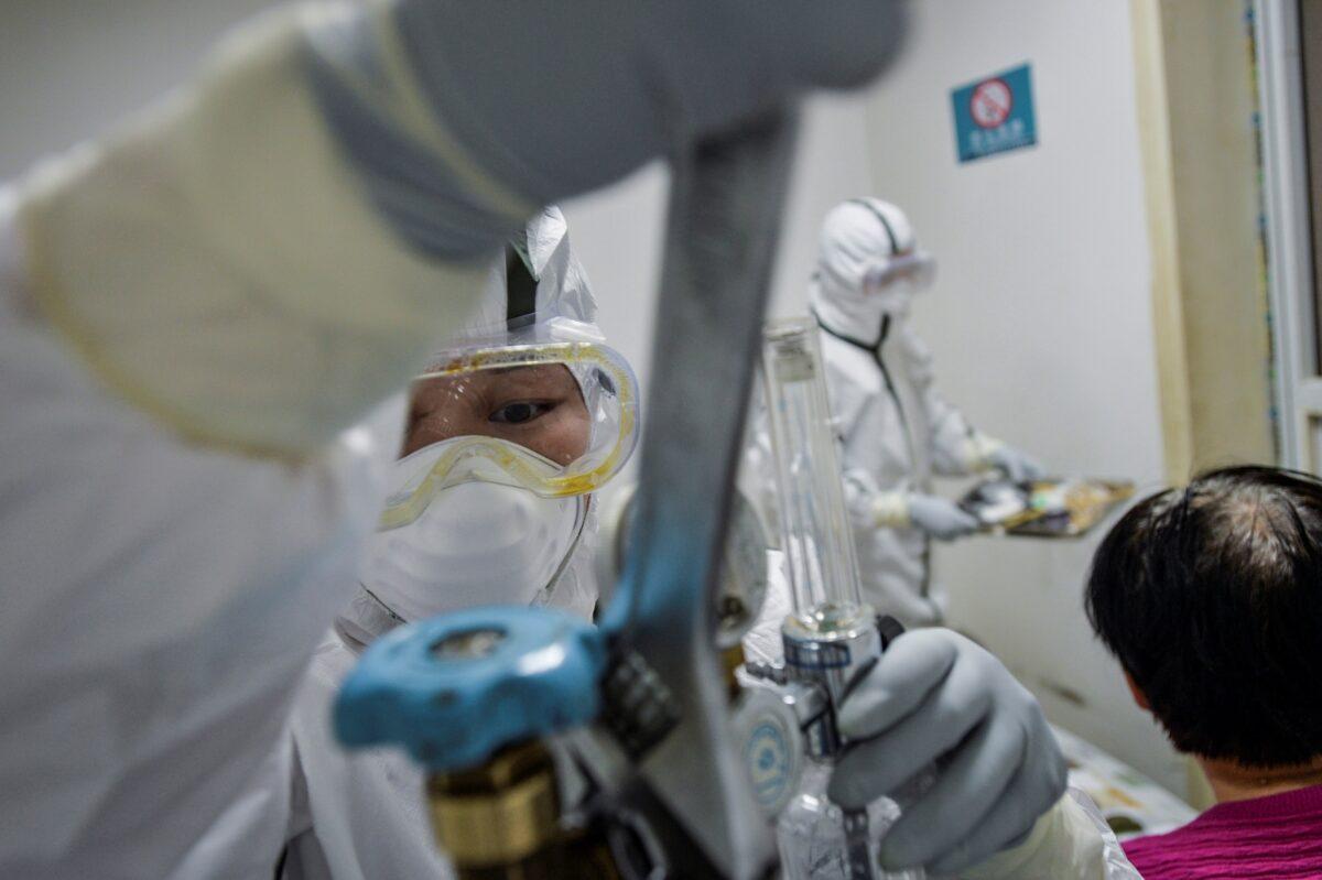 A medical worker in protective suit replaces an oxygen tank for a patient at a community health service center, which has an isolated section to receive patients with mild symptoms caused by the novel coronavirus and suspected patients of the virus, in Qingshan district of Wuhan in Hubei Province, China on Feb. 8, 2020. (China Daily via Reuters)