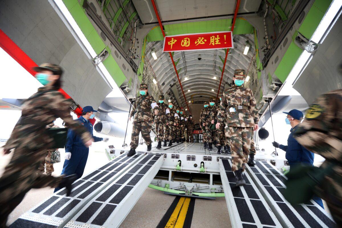 Medical personnel arrive with medical supplies in a transport aircraft of the Chinese People's Liberation Army Air Force at the Wuhan Tianhe International Airport following the outbreak of the Novel Coronavirus in Wuhan, China, on Feb. 13, 2020. (China Daily via Reuters)