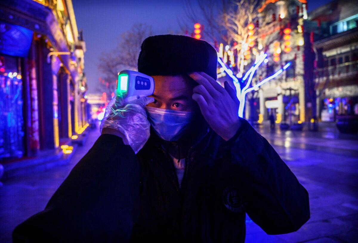 A Chinese worker wears a protective mask as he has his temperature checked in a nearly empty and shuttered commercial street in Beijing on Feb. 12, 2020. (Kevin Frayer/Getty Images)