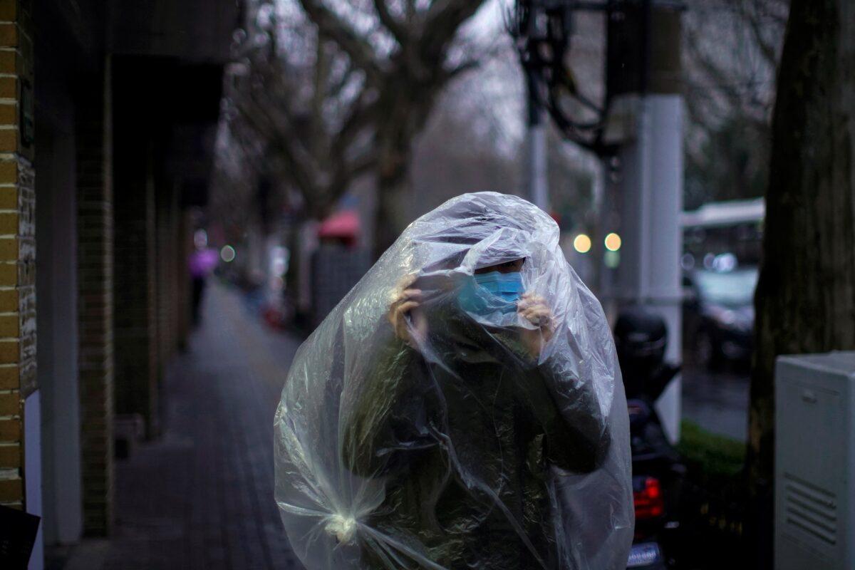 A man wearing a mask and covered with a plastic bag walks on a street in Shanghai, China, as the country is hit by an outbreak of the novel coronavirus on Feb. 13, 2020. (Aly Song/Reuters)