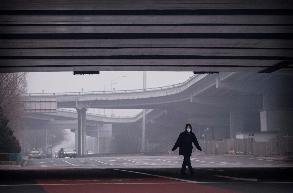A Chinese woman wears a protective mask as she crosses a nearly empty intersection in Beijing, China on Feb. 13, 2020. (Kevin Frayer/Getty Images)