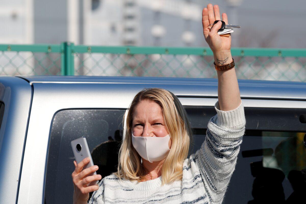 A woman waves from outside Daikoku Pier Cruise Terminal as she communicates via phone with a passenger (not pictured) standing on the balcony of a cabin on the cruise ship Diamond Princess, as the vessel's passengers continue to be tested for coronavirus, in Yokohama, Japan, on Feb. 13, 2020. (Kim Kyung-Hoon/Reuters)