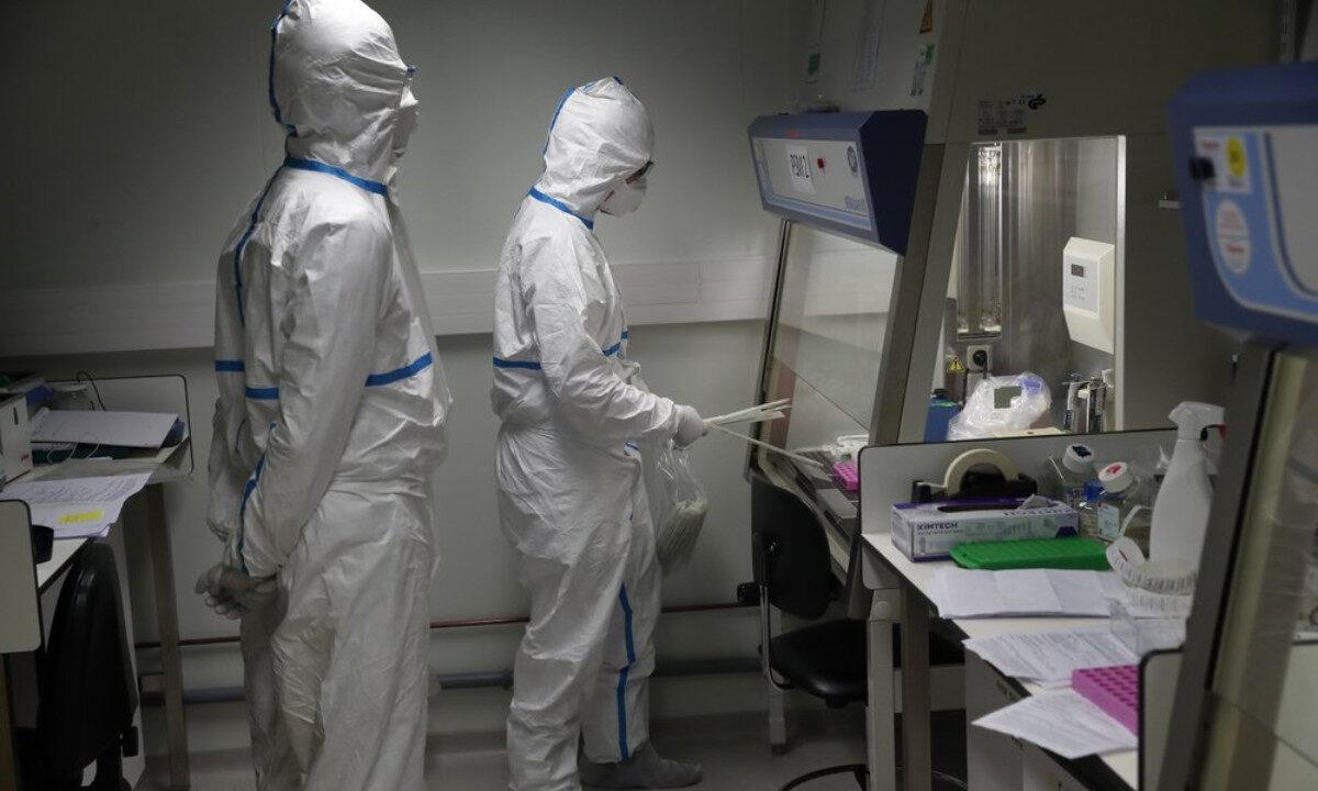 French lab scientists in hazmat gear inserting liquid in test tube manipulate potentially infected patient samples at Pasteur Institute in Paris, on Feb. 6, 2020. (Francois Mori/AP Photo)