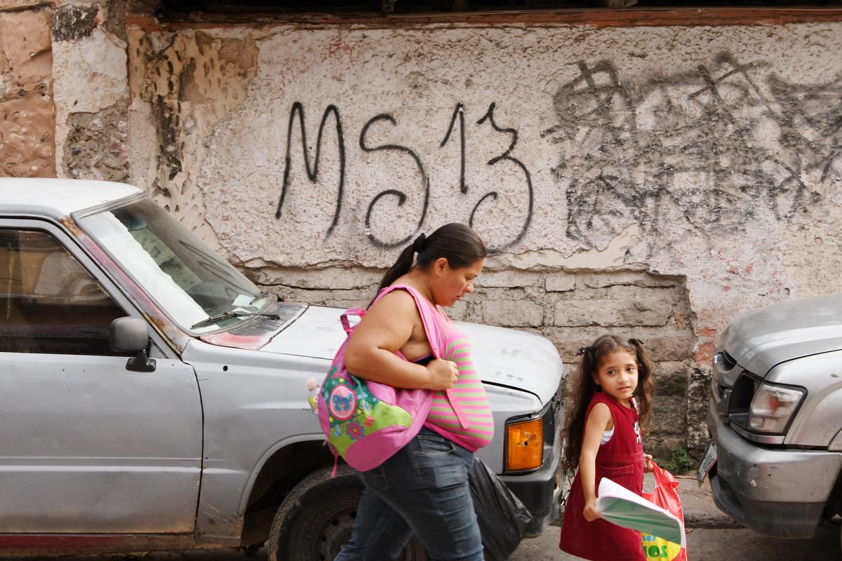 Local residents pass by a grafitti made by the Mara Salvatrucha (MS-13) gang in the MS-13-controlled El Bosque neighborhood in Tegucigalpa, Honduras, on May 9, 2017. (Orlando Sierra/AFP via Getty Images)