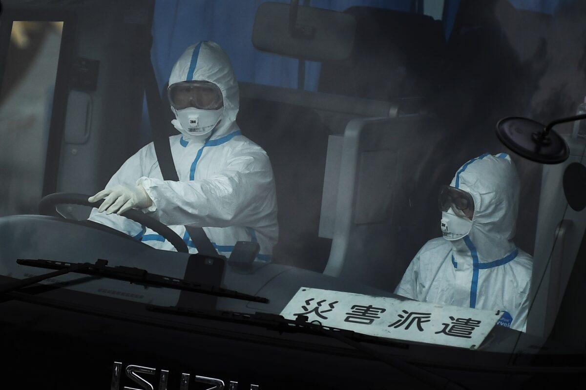 A bus with a driver wearing full protective gear departs from the dockside next to the Diamond Princess cruise ship, which has around 3,600 people quarantined onboard due to fears of the new COVID-19 coronavirus, at the Daikoku Pier Cruise Terminal in Yokohama port, Japan, on Feb. 14, 2020. (Charly Triballeau/AFP via Getty Images)
