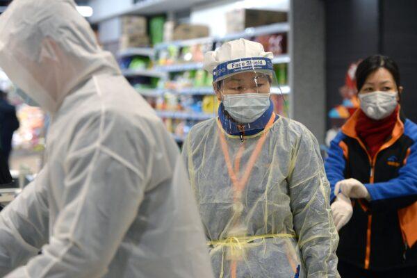 A staff member wearing a protective mask and suit works at a supermarket in Wuhan, the epicenter of the outbreak of a novel coronavirus, in China's central Hubei province on Feb. 10. (STR/AFP via Getty Images)