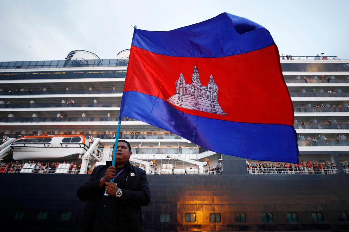 A Cambodian man holds his national flag in front of the MS Westerdam, owned by Holland America Line, docked in Sihanoukville, Cambodia on Feb. 14, 2020. (Heng Smith/AP Photo)