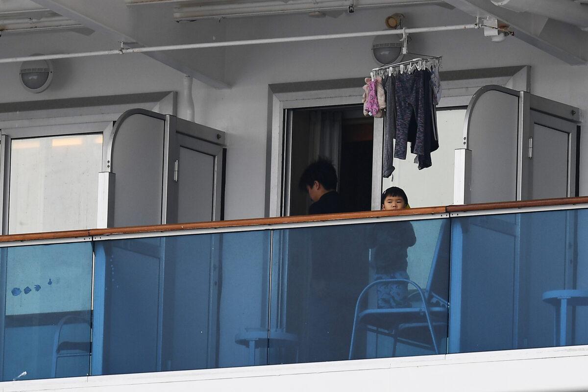 A child looks out from a balcony on the Diamond Princess cruise ship, which has around 3,600 people quarantined onboard due to fears of the new COVID-19 coronavirus, at the Daikoku Pier Cruise Terminal in Yokohama port, Japan, on Feb. 14, 2020. (Charly Triballeau/AFP via Getty Images)