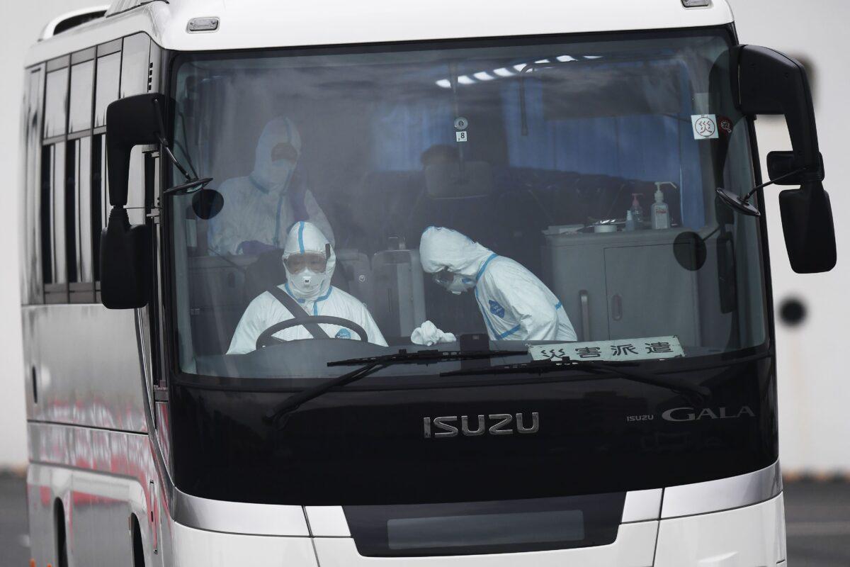 A bus with a driver wearing protective gear departs from the dockside next to the Diamond Princess cruise ship, at the Daikoku Pier Cruise Terminal in Yokohama port, Japan, on Feb. 14, 2020. (Charly Triballeau/AFP via Getty Images)