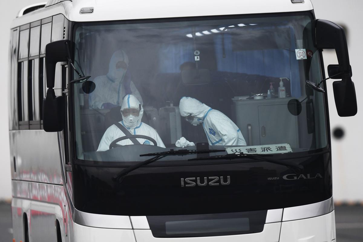 A bus with a driver wearing protective gear departs from the dockside next to the Diamond Princess cruise ship, which has around 3,600 people quarantined onboard due to fears of the new COVID-19 coronavirus, at the Daikoku Pier Cruise Terminal in Yokohama port, Japan, on Feb. 14, 2020. (Charly Triballeau/AFP via Getty Images)