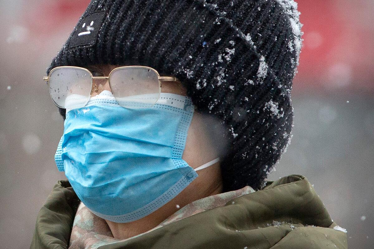 A woman's eyeglasses are fogged up as she wears a face mask during a snowfall in Beijing on Feb. 2, 2020. (Mark Schiefelbein/AP Photo)