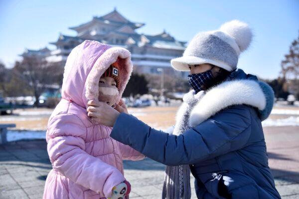 A woman helps her daughter seen wearing a face mask in Pyongyang on Feb. 6, 2020. (Kim Won-Jin/AFP via Getty Images)