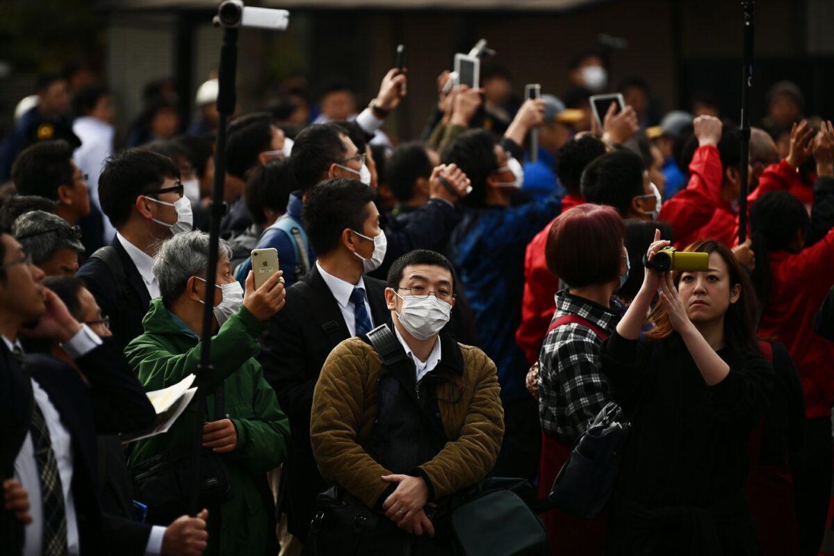 People wearing face masks look on during a rehearsal of the Tokyo 2020 Olympics torch relay in Tokyo on Feb. 15, 2020. (Charly Triballeau/AFP via Getty Images)